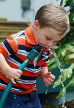 child drinking from hose